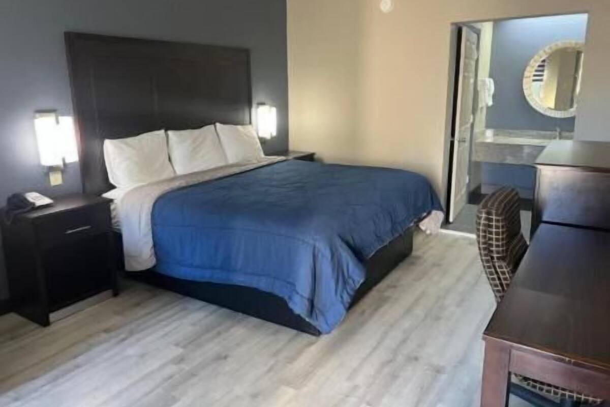 A hotel room with a bed, bedside table, and a dresser.