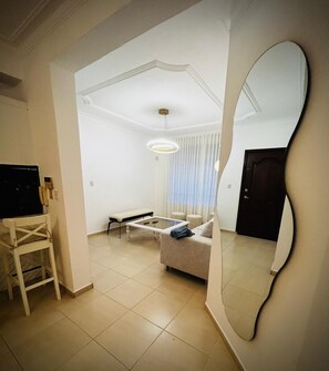 A living room with a sofa, coffee table, TV, and a large mirror. - Cozy 2-bedroom apartment in perfect Santiago de los Caballeros with AC (Santiago de los Caballeros)
