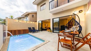 Un área de piscina con jacuzzi, mobiliario exterior y una mesa de comedor con sillas.