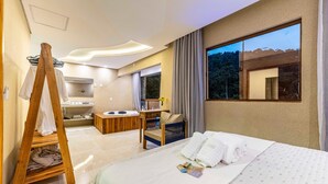 Ein Hotelzimmer mit Bett, einem Holzregal mit Handtüchern, einem Badezimmer mit Waschbecken und Spiegel sowie einem großen Fenster mit Blick.