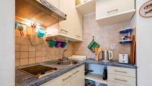 Een keuken met een spoelbak, fornuis en diverse keukengerei.