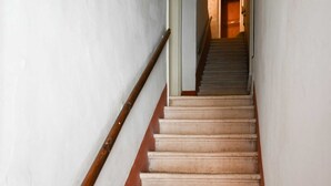 Een trap met houten leuningen en beige treden die uitkomen op een plateau.