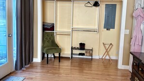 A room with a wooden floor, a green armchair, a patterned rug, a shoe rack, and a dresser. - Quaint 1-bedroom house in charming Friday Harbor perfect for getaway (Friday Harbor)