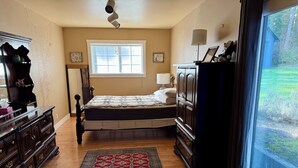 A bedroom with a bed, dresser, window, and a view of the outdoors. - Quaint 1-bedroom house in charming Friday Harbor perfect for getaway (Friday Harbor)