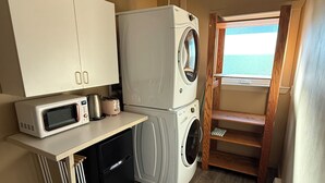 A compact kitchen with a microwave, washing machine, and a small refrigerator. - Quaint 1-bedroom house in charming Friday Harbor perfect for getaway (Friday Harbor)