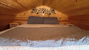 A wooden interior with a bed, pillows, and a decorative headboard. - Cozy Two Loft Tiny House Cabin near beautiful Roaring River with AC (Cassville)