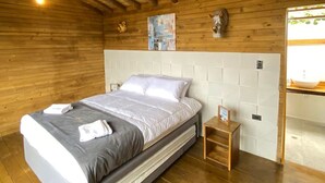 Een slaapkamer in blokhutstijl met een bed, nachtkastje en een hanglamp.