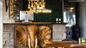 Een restaurant met een houten plafond, hartvormige hanglampen, een olifantbeeld en een neonbord.