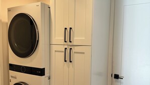 A laundry room with two washing machines, a tall cabinet, and a door.