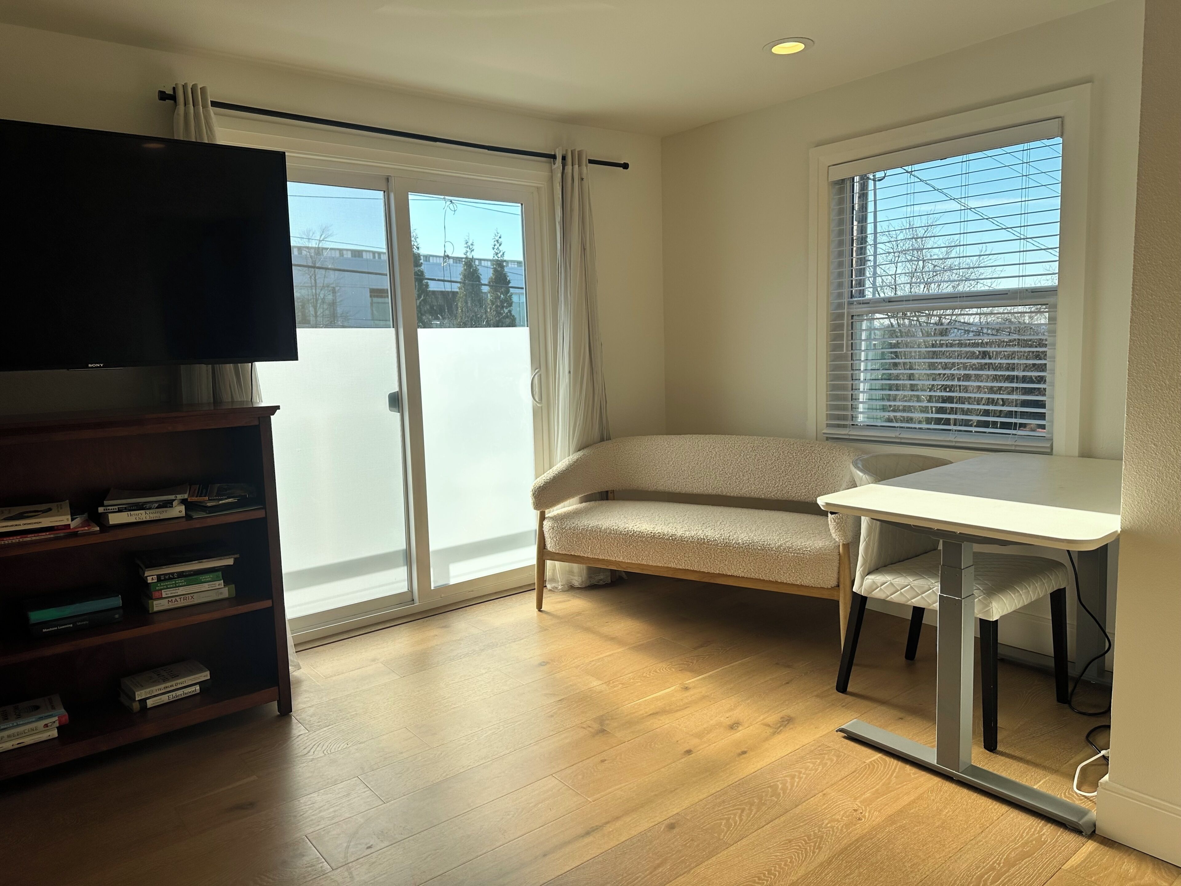 A room with a sliding glass door, a sofa, a small table, and a bookshelf.