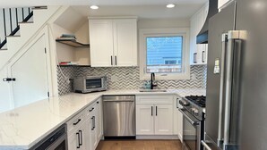 A modern kitchen with white cabinets, a stainless steel refrigerator, a built-in oven, a microwave, and a dishwasher.