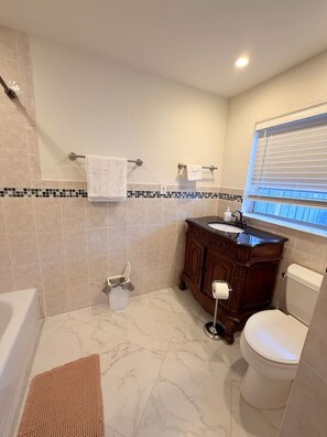 A bathroom with a bathtub, toilet, vanity, and a window. - Couple Suite•Private Bath• Garden•Private entry (Wilton Manors)