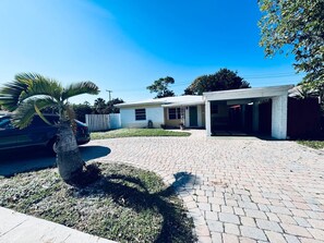 A residential property with a paved driveway, a covered porch, and a palm tree. - Fort Lauderdale Gem Private Yard and Patio (Fort Lauderdale)