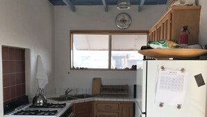 A compact kitchen with a gas stove, white refrigerator, wooden cabinets, and a window with a view.