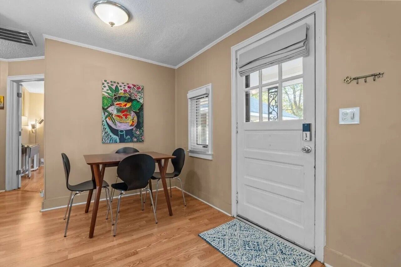 Un espace repas comprenant une table et des chaises, une porte avec une fenêtre et un luminaire fixé au mur.