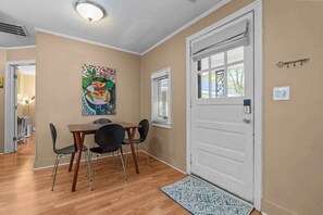 A dining area with a table and chairs, a door with a window, and a wall-mounted light fixture. - Windmere Cottage in Charming Pinehurst (Pinehurst)