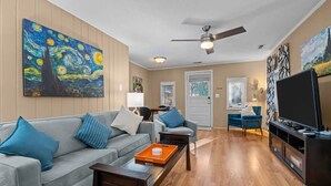 A living room with a sofa, coffee table, and artwork on the walls. - Windmere Cottage in Charming Pinehurst (Pinehurst)