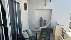 En uteplats med en hängmatta, en soffa med mönstrade kuddar och ett litet bord med en växt.