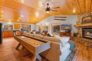A cozy living room with a pool table, a fireplace, and a stone accent wall. - Pine Cottage (Big Bear Lake)