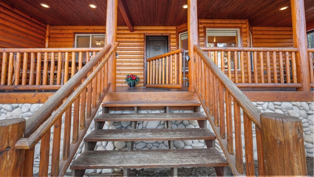 A wooden cabin with a stone foundation, a wooden staircase with a railing, and a door with a window above it. - Pine Cottage (Big Bear Lake)