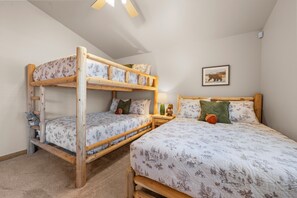 A room with two bunk beds, a small table with a lamp, and a framed picture on the wall. - Pine Cottage (Big Bear Lake)
