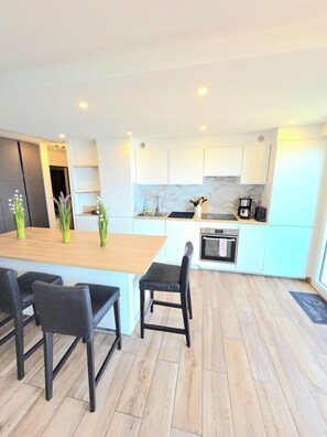 A modern kitchen with white cabinets, a wooden island, and a built-in oven. - Air-conditioned apartment, fantastic sea view, tramway and amenities nearby (Nice)
