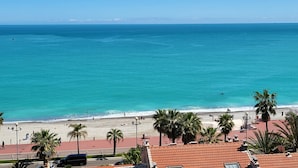 Blick auf die Küste mit Strand, Palmen und blauem Himmel.