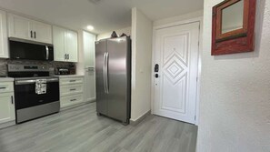 A kitchen with white cabinets, a stainless steel refrigerator, a microwave, and an oven. - Gorgeous Third-Level Condo Princesa D-308 (Puerto Peñasco)