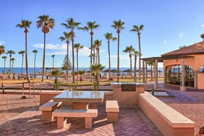Een terras met buitenmeubels, palmbomen en uitzicht op de oceaan.