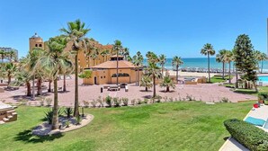 Un complexe hôtelier doté d’une piscine, de palmiers et offrant une vue sur la plage.