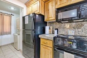 A kitchen with wooden cabinets, a black refrigerator, a microwave, a stove, and a washing machine. - Stunning Views in 2nd Level Condo Princesa B-203 (Puerto Peñasco)