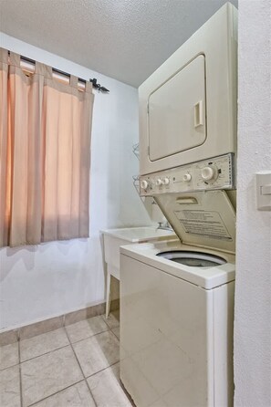 A compact laundry area with a washing machine, a drying rack, and a small sink. - Stunning Views in 2nd Level Condo Princesa B-203 (Puerto Peñasco)