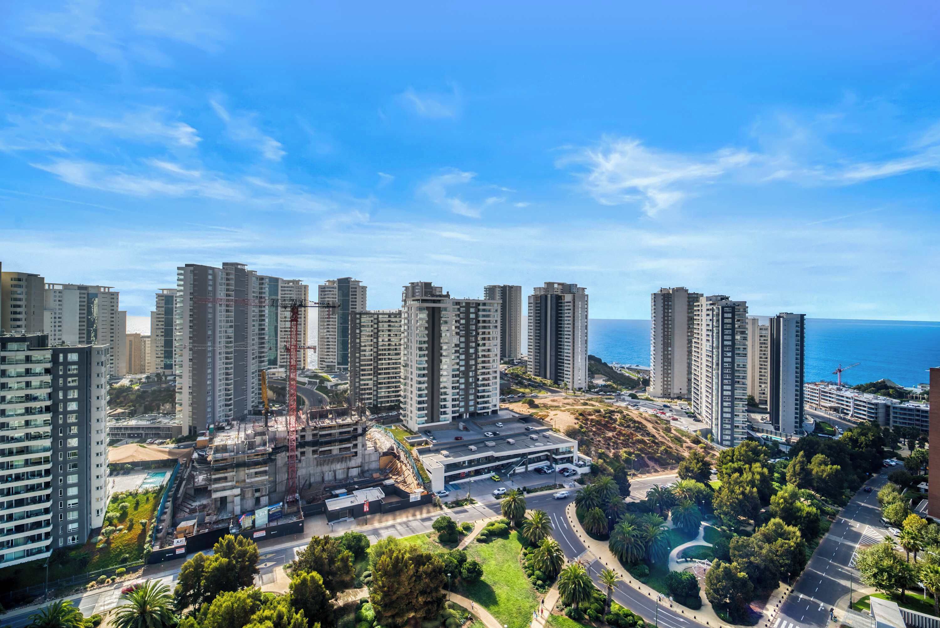A high-rise residential area with multiple apartment buildings, a construction site, and a road with greenery.
