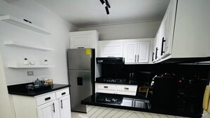 Una cocina moderna con armarios blancos, una encimera negra y un refrigerador empotrado.