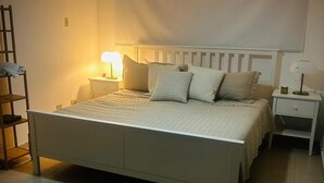 Un dormitorio con cama, mesitas de noche, lámpara, escalera y equipo de aire acondicionado.