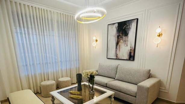 Una sala de estar con un sofá, una mesa de centro, un banco y un cuadro en la pared.
