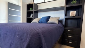 Un dormitorio con cama, estanterías empotradas y una ventana.