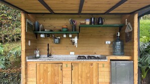 A wooden outdoor kitchen with a sink, stove, and storage cabinets.