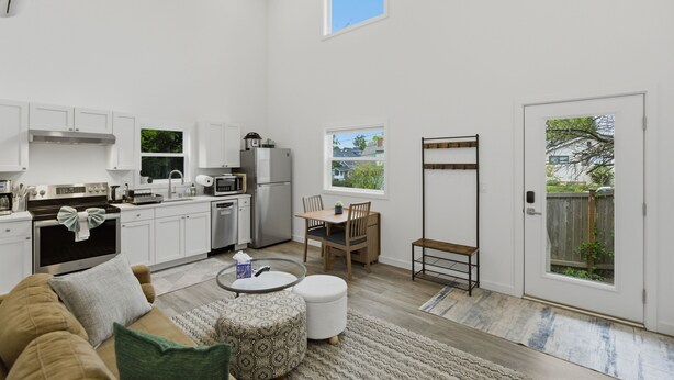 A spacious kitchen with white cabinets, a dining area with a table and chairs, and a large window providing a view of the outdoors. - Peaceful Central District Retreat 3 bdrm, patio (Seattle)