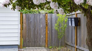 A wooden fence with a mailbox and a small tree in front. - Peaceful Central District Retreat 3 bdrm, patio (Seattle)