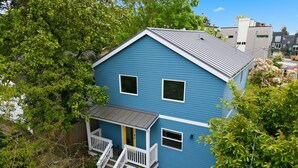 A two-story house with a blue exterior, white trim, and a small porch with steps. - Peaceful Central District Retreat 3 bdrm, patio (Seattle)