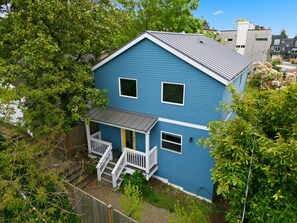 Ein zweistöckiges Haus mit blauer Fassade, weißem Zierdekor und einer kleinen Veranda mit Stufen.