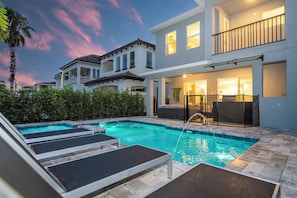 Ein Wohnhaus mit Swimmingpool, Liegestühlen und einem zweistöckigen Gebäude mit Balkonen.