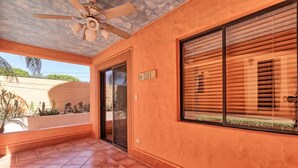 A covered outdoor area with a ceiling fan, a sliding glass door, and a window with blinds. - Charming Colorful Condo Near Pool - Pueblos D-101 (Puerto Peñasco)