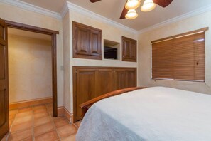 A bedroom with a bed, wooden cabinets, a ceiling fan, and a window with blinds. - Charming Colorful Condo Near Pool - Pueblos D-101 (Puerto Peñasco)