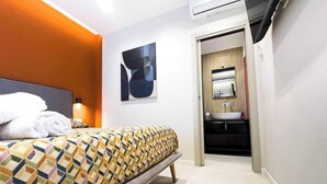A hotel room with a bed, a bathroom with a sink, and a painting on the wall. - Vesuvio | Penthouse Pignasecca – Design Suite (Naples)
