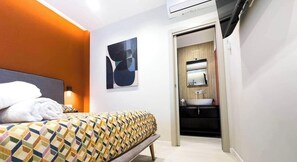 Ein Hotelzimmer mit Bett, einem Badezimmer mit Waschbecken und einem Gemälde an der Wand.
