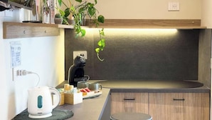 Uma cozinha compacta com fogão embutido, cafeteira e chaleira no balcão.