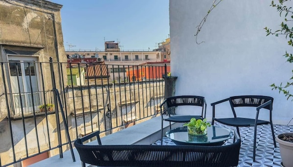 Ein Balkon mit Tisch, Stühlen und einem Blumentopf.