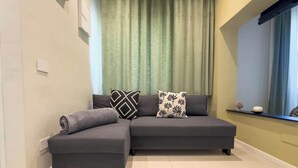 Uma sala de estar moderna com sofá modular, uma janela com vista e cortina.